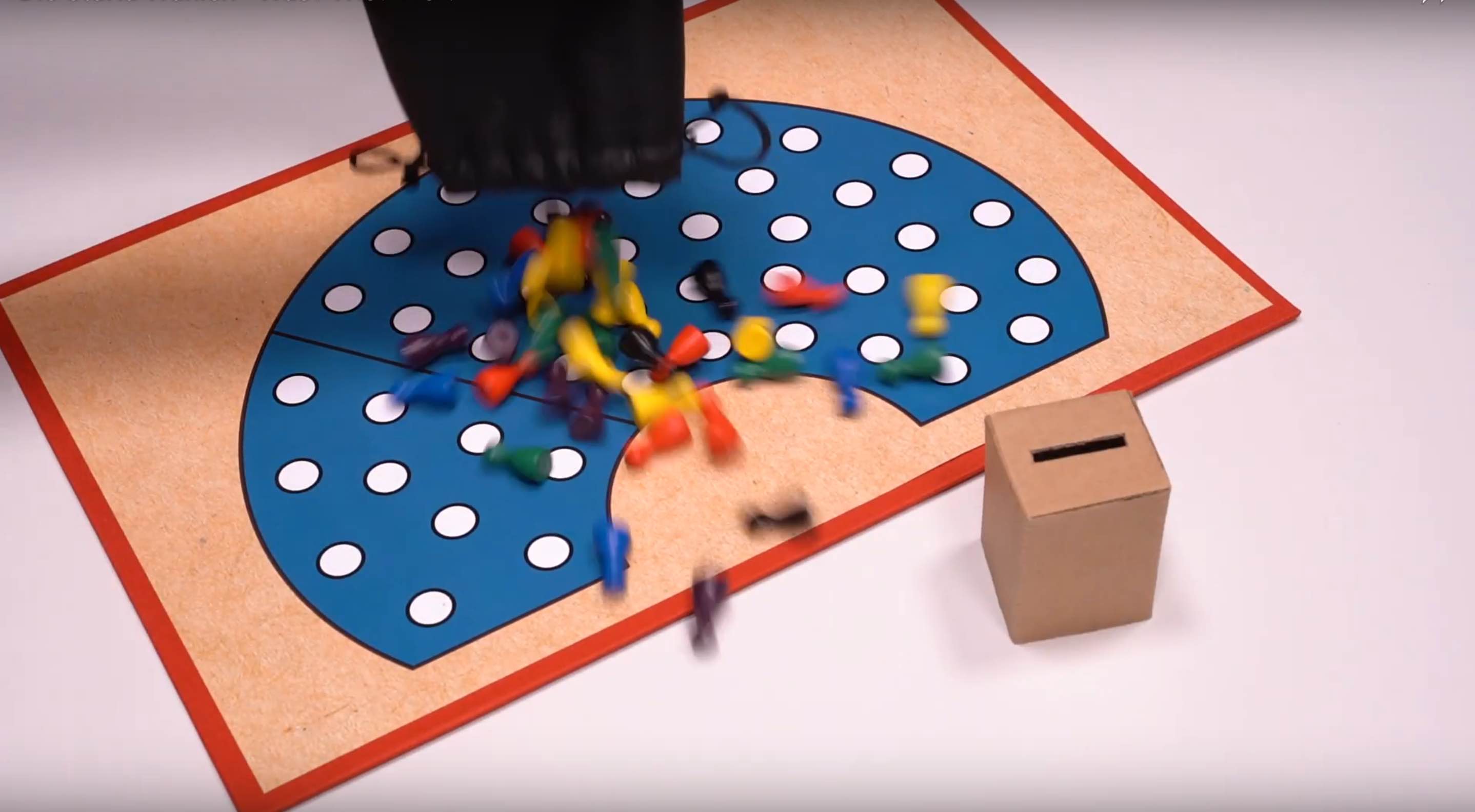 Videostill: Figuren werden auf Spielbrett geschüttet