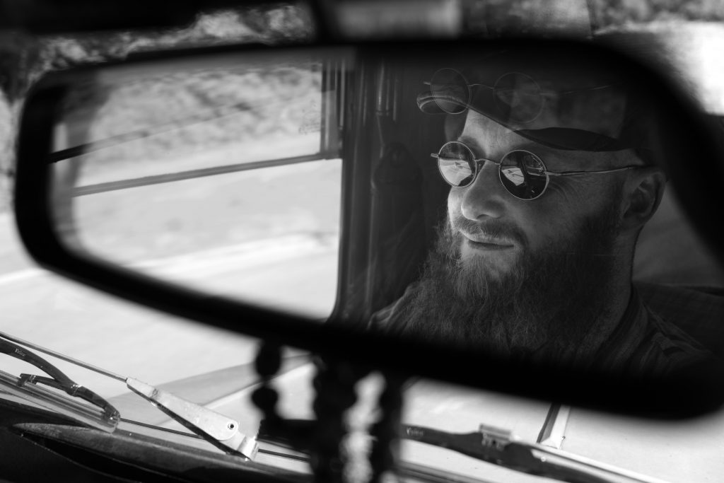 Mann mit Sonnenbrille im Rückspiegel